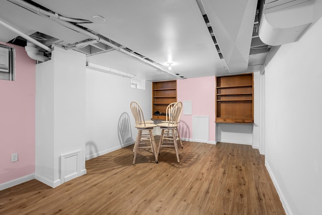 dining room featuring built in shelves and wood-type flooring