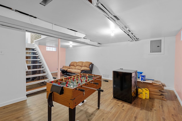 recreation room featuring electric panel and light hardwood / wood-style flooring