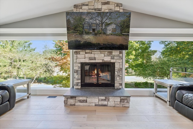 living room with wood-type flooring, lofted ceiling, and an outdoor stone fireplace