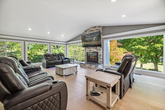 living room with plenty of natural light, a fireplace, vaulted ceiling, and light hardwood / wood-style flooring