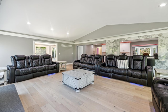 living room featuring lofted ceiling and light hardwood / wood-style floors