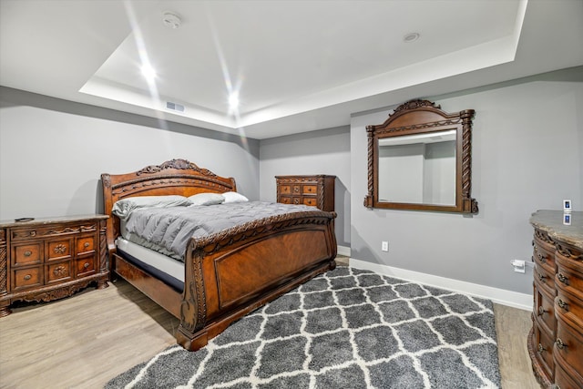 bedroom featuring hardwood / wood-style floors and a tray ceiling