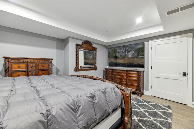 bedroom with a tray ceiling and light hardwood / wood-style flooring