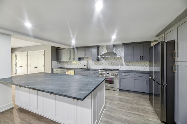 kitchen with appliances with stainless steel finishes, a breakfast bar, sink, and wall chimney exhaust hood