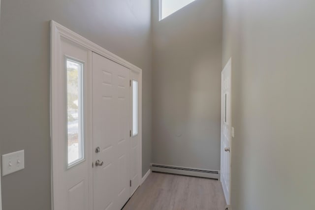 entrance foyer featuring a high ceiling, baseboard heating, and light hardwood / wood-style floors