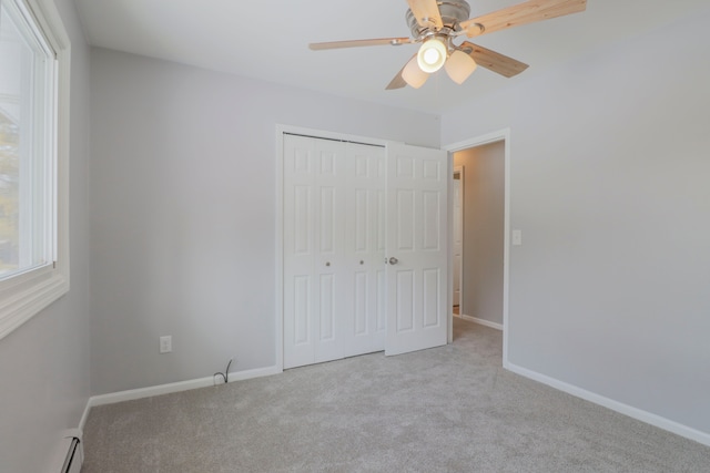 unfurnished bedroom with light colored carpet, a closet, ceiling fan, and baseboard heating