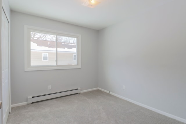 empty room featuring baseboard heating and light colored carpet