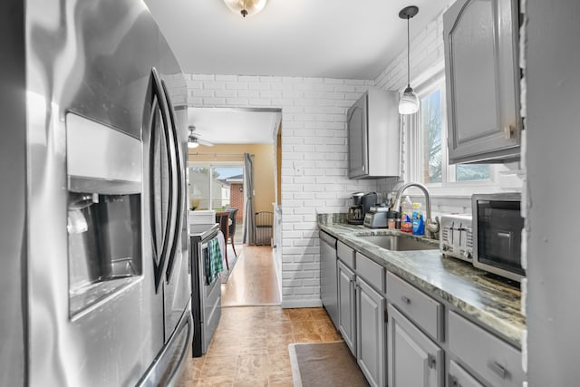 kitchen with gray cabinets, pendant lighting, sink, stainless steel appliances, and plenty of natural light