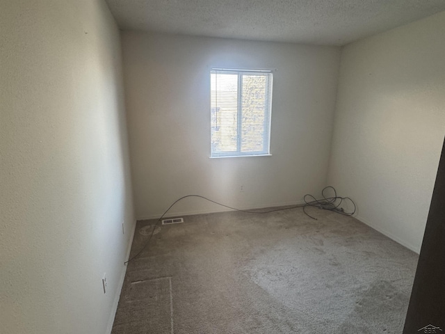 carpeted empty room featuring a textured ceiling