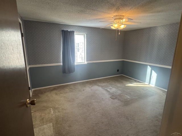 empty room featuring ceiling fan, carpet flooring, and a textured ceiling