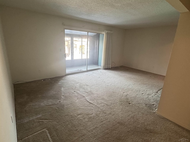 carpeted spare room featuring a textured ceiling