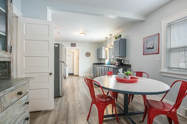 dining room featuring beamed ceiling and light hardwood / wood-style flooring