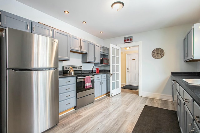 kitchen featuring stainless steel appliances, gray cabinetry, and light hardwood / wood-style flooring