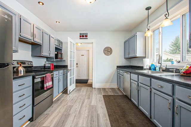 kitchen with sink, decorative light fixtures, light wood-type flooring, appliances with stainless steel finishes, and gray cabinets