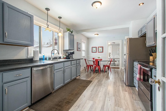 kitchen featuring pendant lighting, sink, appliances with stainless steel finishes, gray cabinetry, and light hardwood / wood-style floors