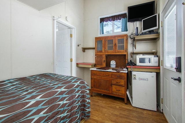 bedroom featuring refrigerator and hardwood / wood-style floors