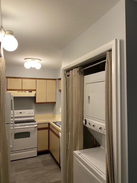 kitchen featuring stacked washer and dryer, dark wood-type flooring, light brown cabinetry, and white appliances