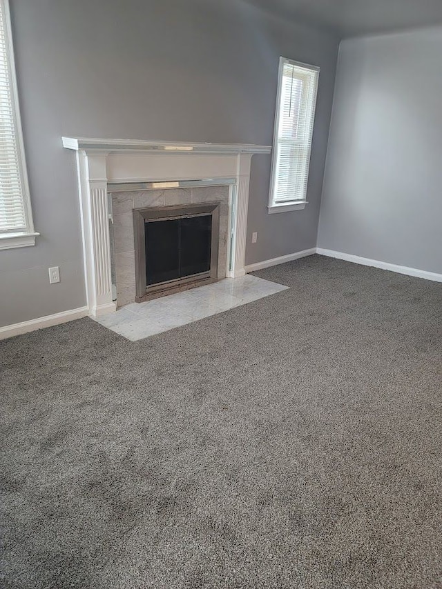 unfurnished living room featuring a tiled fireplace and carpet floors