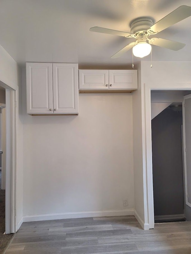 kitchen with light wood-type flooring, white cabinets, and ceiling fan