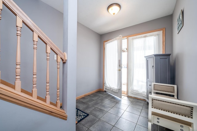 tiled foyer entrance featuring stairway and baseboards