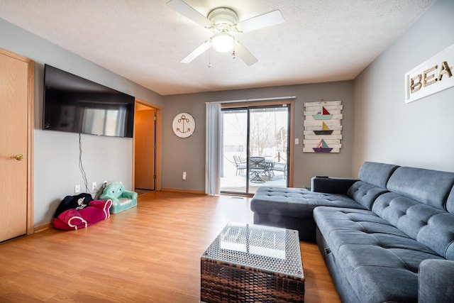 living room with baseboards, a textured ceiling, ceiling fan, and wood finished floors