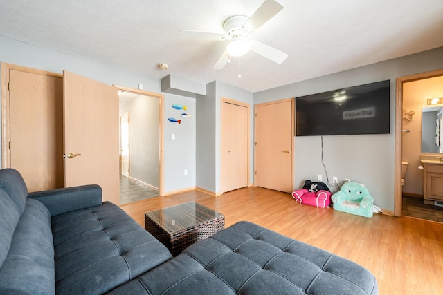 living area featuring baseboards, light wood-type flooring, and a ceiling fan