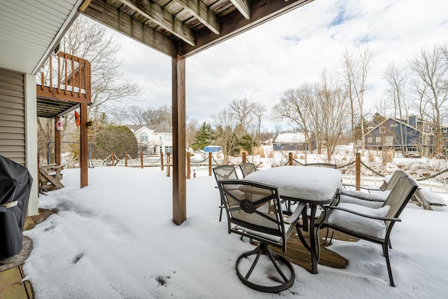 snow covered patio featuring grilling area, a residential view, and outdoor dining space