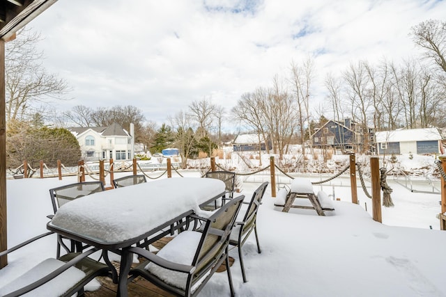 snow covered patio with a residential view and outdoor dining space