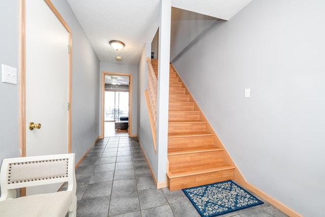 stairs with tile patterned floors, baseboards, and a textured ceiling