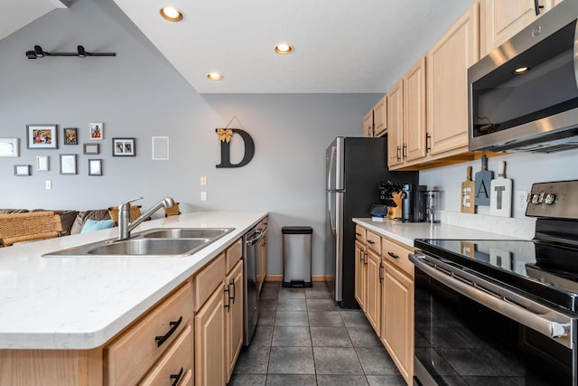 kitchen featuring light brown cabinets, a sink, open floor plan, recessed lighting, and appliances with stainless steel finishes