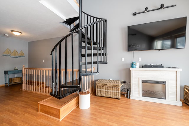 stairs featuring a glass covered fireplace and wood finished floors