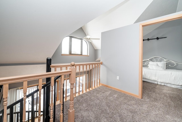 corridor with vaulted ceiling, an upstairs landing, carpet, and baseboards