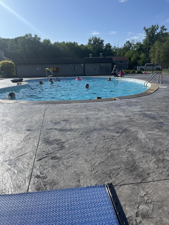 community pool with a patio and fence