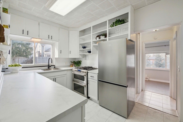 kitchen featuring stainless steel appliances, sink, light tile patterned floors, and white cabinets