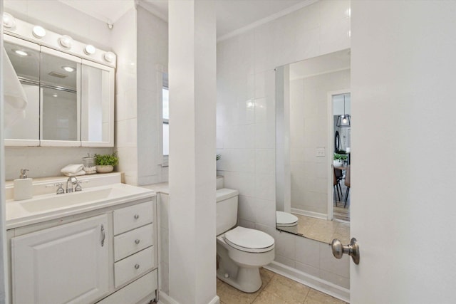 bathroom with tile walls, vanity, toilet, crown molding, and tile patterned floors