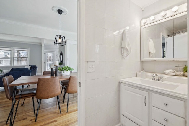 bathroom with tile walls, vanity, hardwood / wood-style flooring, and ornamental molding