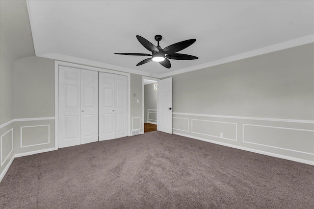 unfurnished bedroom with ceiling fan, crown molding, dark carpet, and a closet