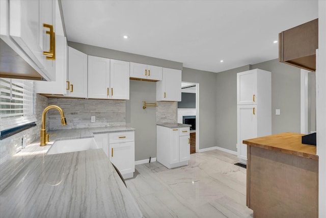 kitchen with white cabinetry, wood counters, sink, and decorative backsplash