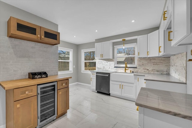 kitchen with white cabinetry, sink, stainless steel dishwasher, and beverage cooler