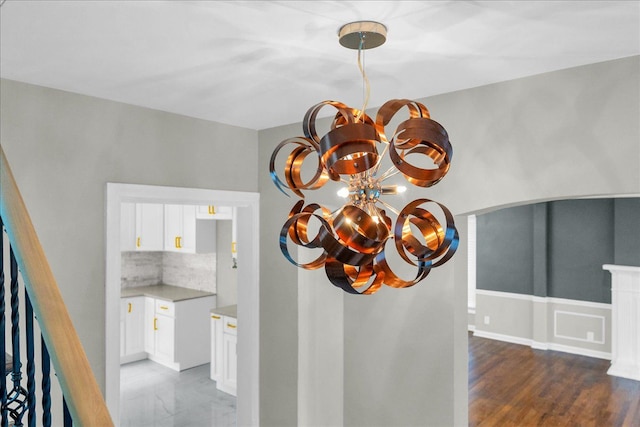 details featuring an inviting chandelier, decorative backsplash, and hardwood / wood-style flooring