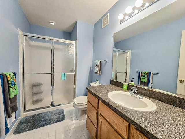 bathroom with tile patterned flooring, vanity, a shower with door, and toilet