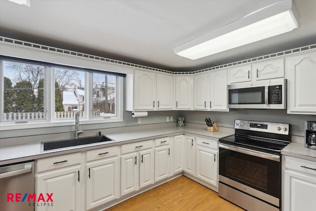 kitchen with sink, light hardwood / wood-style flooring, white cabinets, and appliances with stainless steel finishes