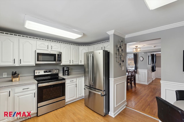 kitchen with white cabinetry, crown molding, stainless steel appliances, and light hardwood / wood-style floors