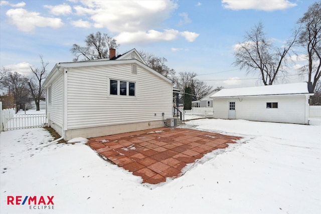 snow covered back of property featuring an outdoor structure and central AC