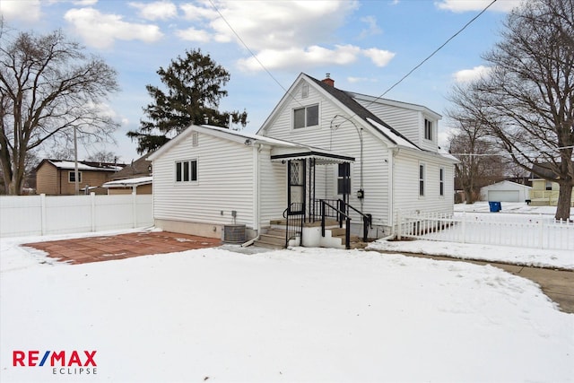 snow covered house featuring central air condition unit