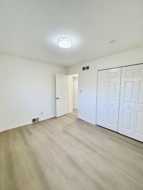 unfurnished bedroom featuring light hardwood / wood-style flooring and a closet