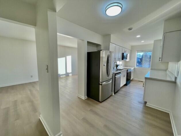 kitchen with sink, stainless steel appliances, light hardwood / wood-style floors, and white cabinets