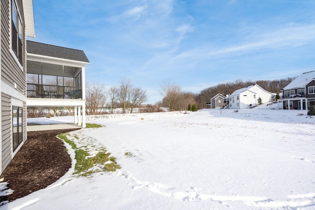 yard layered in snow featuring a sunroom