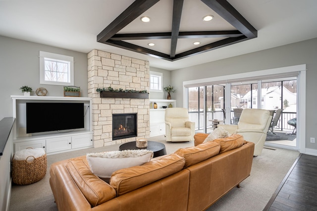 living room with beamed ceiling, a healthy amount of sunlight, and a fireplace