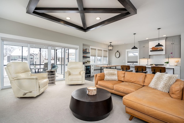 living room featuring sink, beam ceiling, wine cooler, coffered ceiling, and light carpet